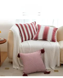 Detail of red and white striped cotton throw pillow case featuring decorative fringe tassels