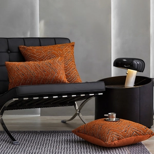 Terracotta chenille pillows with wave patterns on a leather chair in a modern room