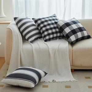 Minimalist black and white plaid and striped throw pillow covers on a cozy sofa