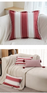 Close-up of red and white striped throw pillow with decorative fringe and canvas texture