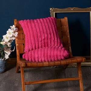 Plush rose red throw pillow and bolster set with 3D stripes on a brown woven chair
