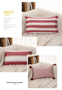 Detailed view of red and white striped cushions with decorative fringes on a cozy blanket