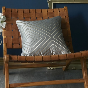Luxury geometric square cushion cover in silver satin with gold diamond lines on leather chair