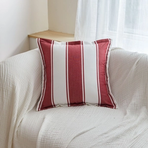 Red and white vertical striped cotton pillowcase with piped edges on a sofa