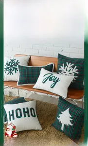 Detail of Christmas pillow featuring red and green plaid embroidery and Joy text