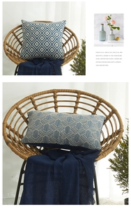 Detail der blauen Kissenhülle mit weißem Webmuster auf einem Rattansessel im Wohnzimmer