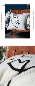 Detailaufnahme weißer Kissenbezug aus Teddy-Fleece mit schwarzer abstrakter Gesicht-Stickerei