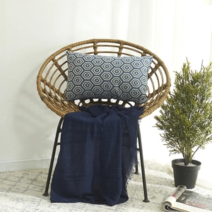 Blauer Baumwoll-Lendenkissenbezug mit weißem Sechseck-Muster auf einem Rattansessel