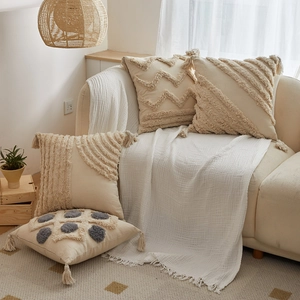 Fodere per cuscini in stile boho con nappe su divano beige in un soggiorno accogliente
