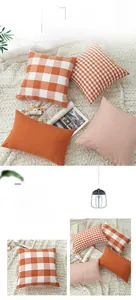Detail showing orange plaid and striped decorative cushion covers on a soft rug
