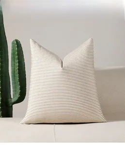 Detail of a brown and white striped Nordic throw pillow on an off-white sofa