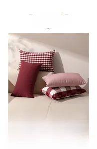 Detail of red and white plaid, striped, and solid pillow covers on a white sofa