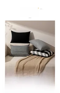 Set of four minimalist black and white plaid and striped pillow covers on a sofa