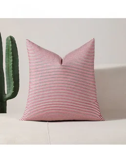 Detail of red and white striped cushion cover on a beige sofa in a Nordic living room