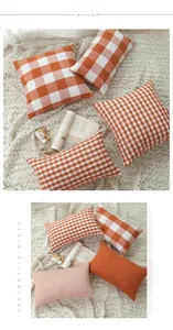 Detailed view of orange and white striped plaid decorative pillowcases on plush rug