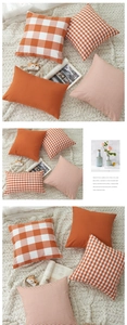 Detail of minimalist orange checkered and striped cushion covers on a soft white rug