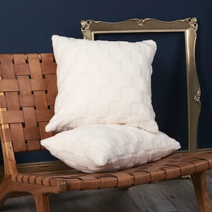 Plush white checkered throw pillows with 3D texture on a modern brown woven chair