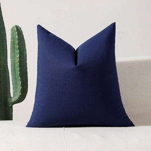 Modern navy blue checkered throw pillow on a beige sofa with minimalist home decor