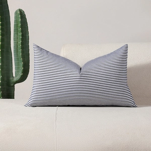 Blue and white striped rectangular lumbar pillow cover on a cozy white plush sofa