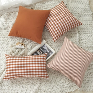 Burnt orange and white minimalist plaid cushion covers on a soft knit blanket