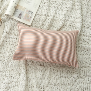 Modern orange and white striped rectangular pillowcase on a soft white knitted blanket