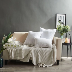 Three plush white pillow inserts in various sizes displayed on a modern beige sofa