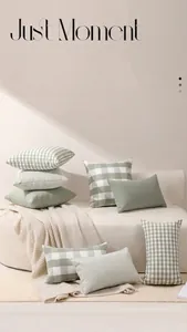 Détail de housses de coussin à carreaux et rayures vertes sur un canapé blanc avec plaid