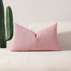 Modern red and white vertical striped lumbar pillow cover on a cozy sofa setting
