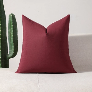 Modern burgundy plaid square throw pillow cover on a white fabric sofa with a cactus decor