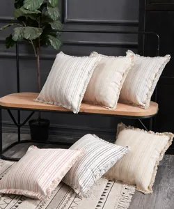 Detail of striped jacquard cushion cover with fringe edges on a wooden bench