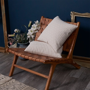 Set of two cream chenille cushion covers with 3D leaf pattern on a stylish leather chair