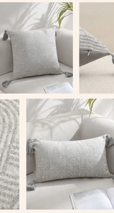 Detail of geometric jacquard fabric and tassel fringe on a modern grey cushion cover