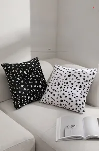 Detail of plush black and white spotted pillow covers on a modern gray sofa