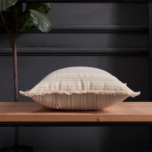 Modern striped jacquard pillow cover with fringe edges on a wooden bench
