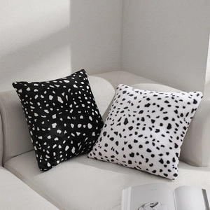 Minimalist black and white spotted plush throw pillows on a light gray modern sofa