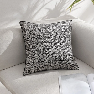 Modern black and white geometric pattern pillow on sofa with natural leaf shadows