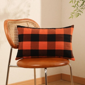 Modern Halloween orange and black buffalo plaid lumbar pillow cover on a nordic chair