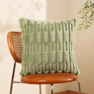 Sage green faux rabbit fur pillow cover with striped texture on a leather chair