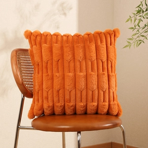 Orange faux fur cushion cover with textured stripe patterns on a vintage leather chair