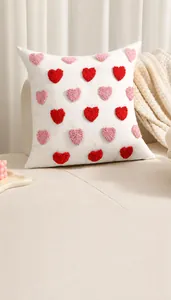 Détails de motifs de cœurs 3D tuftés roses et rouges sur une housse de coussin crème