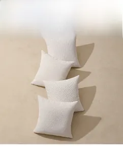 Detailed view of four cream chenille pillow covers with jacquard relief patterns