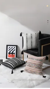Détail de la housse de coussin en chenille jacquard avec rayures et pompons noirs