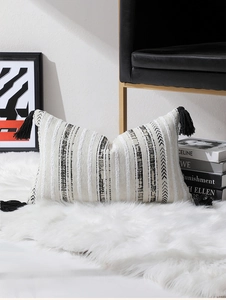 Vue détaillée du coussin lombaire bohème à motifs géométriques et pompons noirs décoratifs