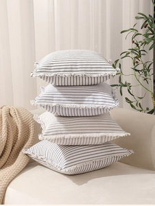 Detail of four striped decorative pillowcases with fringed edges on a sofa