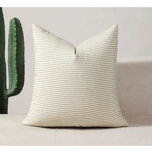 Green and white striped decorative square pillow on a cozy cream-colored sofa