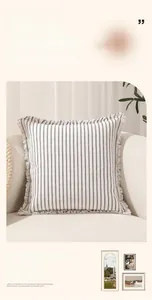 Detail shot of striped cotton cushion cover with fringed edges on a minimalist white sofa