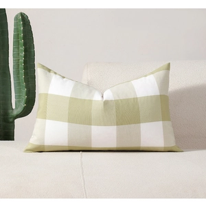 Detail of green and white plaid rectangular cushion on a white sofa in a home setting