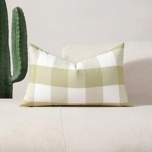 Rectangular green and white gingham throw pillow cushion on a cozy cream sofa