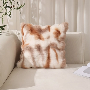 Plush faux rabbit fur pillow cover with beige and brown tie-dye pattern on a sofa