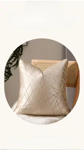 Gros plan d'une housse de coussin satinée or champagne avec bordure géométrique